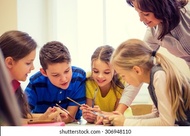 Education, Elementary School, Learning And People Concept - Teacher Helping School Kids Writing Test In Classroom