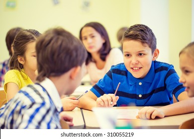 Education, Elementary School, Learning And People Concept - Group Of School Kids Talking During Lesson In Classroom