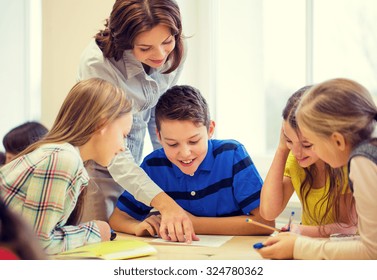 Education, Elementary School, Learning And People Concept - Teacher Helping School Kids Writing Test In Classroom