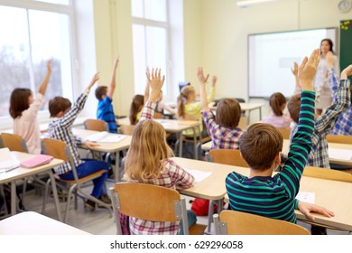 education, elementary school, learning and people concept - group of students raising hands on lesson in classroom - Shutterstock ID 629296058