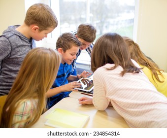 Education, Elementary School, Learning, Technology And People Concept - Group Of School Kids With Tablet Pc Computer Having Fun On Break In Classroom