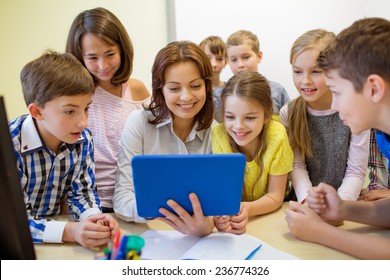 Education, Elementary School, Learning, Technology And People Concept - Group Of School Kids With Teacher Looking To Tablet Pc Computer In Classroom