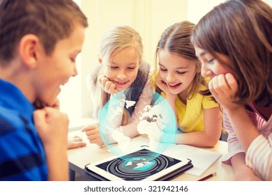Education, Elementary School, Learning, Technology And People Concept - Group Of School Kids Looking To Tablet Pc Computer Screen With Globe Hologram On Break In Classroom
