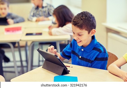 Education, Elementary School, Learning, Technology And People Concept - Little Schoolboy With Tablet Pc Computer On Break In Classroom