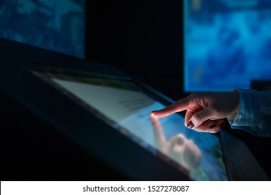 Education, Entertainment , Learning And Technology Concept - Woman Using Interactive Touchscreen Display Of Electronic Kiosk At Modern Museum Or Exhibition