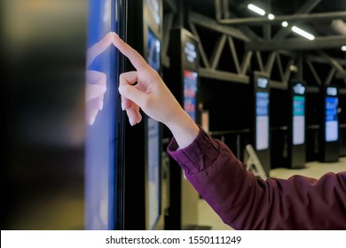 Education, entertainment, learning, technology concept - close up view of woman hand using interactive touchscreen display of electronic kiosk at public transport station - scrolling and touching