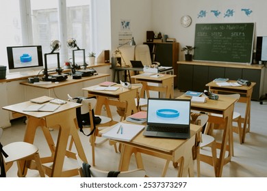 Education environment featuring laptops and 3D printers on wooden tables in classroom setting, including chalkboard, potted plants, and educational posters in background - Powered by Shutterstock