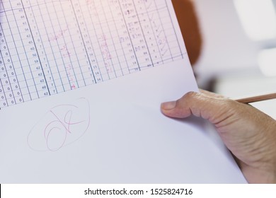 Education evaluation concept : Teacher holding grade tests paper and write OK word in table score report at school. Good grading for student rating for study in university