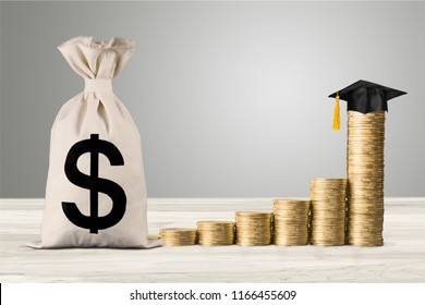 Education Expense Or Student Loan For Post Secondary Education Concept : Dollar Bag, Graduation Cap On Row Of Coins On A Table, Depicts Loan Or Money Designed To Help Students Pay For Associated Fees