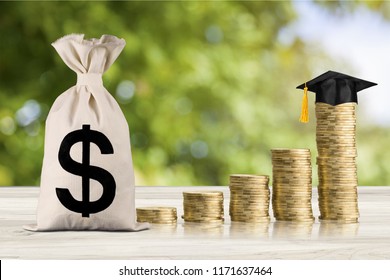 Education Expense Or Student Loan For Post Secondary Education Concept : Dollar Bag, Graduation Cap On Row Of Coins On A Table, Depicts Loan Or Money Designed To Help Students Pay For Associated Fees