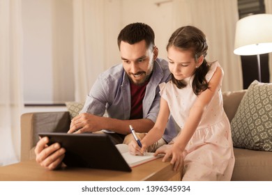 Education And Family Concept - Happy Father And Daughter With Book And Tablet Computer Doing Homework Together At Home