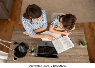 education, family and school concept - mother and son with book , notebook and laptop computer doing homework together at home