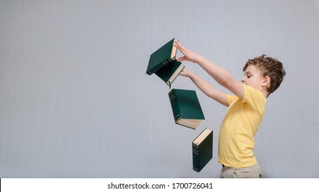 Education Is Funny And Easy Concept. Happy And Smiling Little Boy Child Is Standing On Gray Background And Throw Many Books. Free Space For Text And Logo On Yellow T-shirt