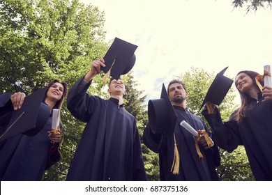 education, graduation and people concept - group of happy international students in mortar boards and bachelor gowns with diplomas - Shutterstock ID 687375136