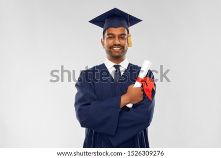 education, graduation and people concept - happy smiling indian male graduate student in mortar board and bachelor gown with diploma over grey background