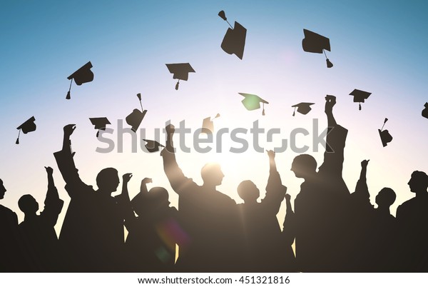 education,\
graduation and people concept - silhouettes of many happy students\
in gowns throwing mortarboards in\
air
