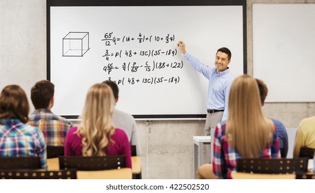 education, high school, mathematics and people concept - smiling teacher standing in front of students and writing mathematical equalities on white board in classroom