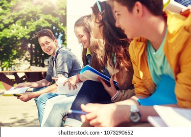 Education, High School And People Concept - Group Of Happy Teenage Students With Notebooks Learning At Campus Yard