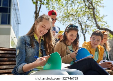 Education, High School And People Concept - Group Of Happy Teenage Students With Notebooks Learning At Campus Yard