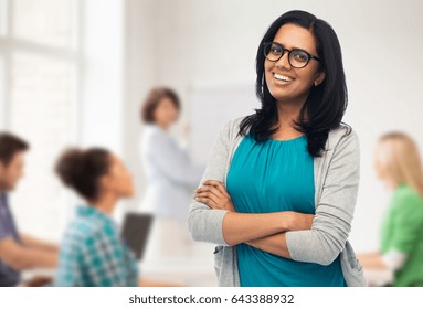 education, high school and people concept - happy smiling young indian woman or teacher in glasses over classroom background - Shutterstock ID 643388932