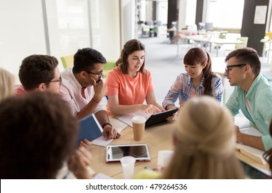 Education, High School, People And Technology Concept - Group Of International Students Sitting At Table With Tablet Pc Computers, Books And Notebooks At University