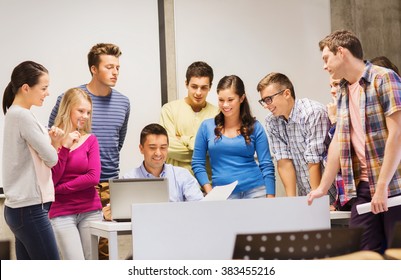 Education, High School, Technology And People Concept - Group Of Smiling Students And Teacher With Papers, Laptop Computer In Classroom