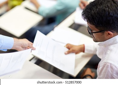 education, high school, university, learning and people concept - teacher giving exam test to indian student man at lecture - Shutterstock ID 512857000