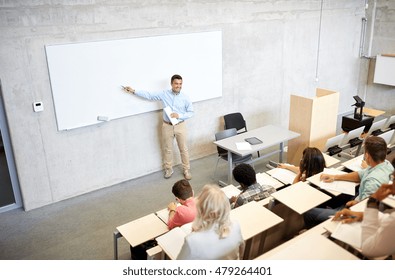 education, high school, university, teaching and people concept - group of international students and teacher with marker standing at white board at lecture