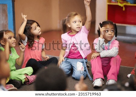 Education, kindergarten and kids asking a question with hands raised while sitting on a classroom floor for child development. School, learning or curiosity with children in class to study for growth