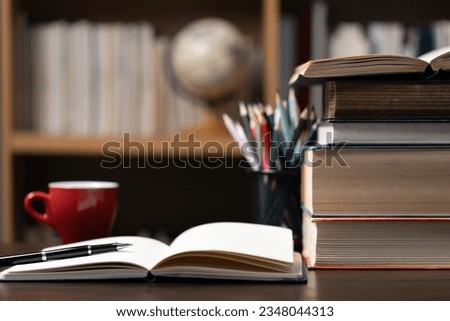 Education learning concept. Book in library with old open textbook, stack piles of literature text archive on reading desk, aisle of bookshelves in school study class room background for academic