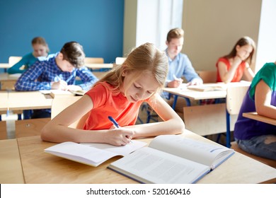 education, learning and people concept - student girl with book writing school test - Shutterstock ID 520160416