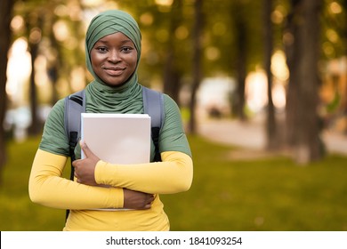 Education For Muslim Women. Smiling Black Student Lady In Hijab Standing Outdoors With Workbooks, Carrying Backpack And Posing To Camera, Islamic Femle Having Free Time At Campus Park, Copy Space