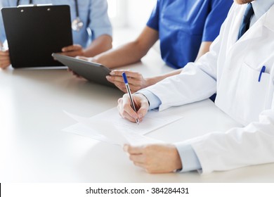 education, profession, people and medicine concept - close up of happy doctors with tablet pc computer and papers at seminar or hospital