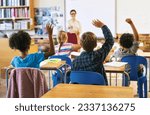 Education, question with group of children in classroom and raise their hands to answer. Learning or support, diversity and teacher teaching with young students in class of school building together