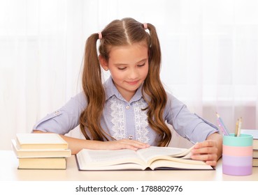 Bildungs- und Schulkonzept. Das Kind sitzt am Schreibtisch und liest ein Buch. Cute kleine Schülerin lernt.