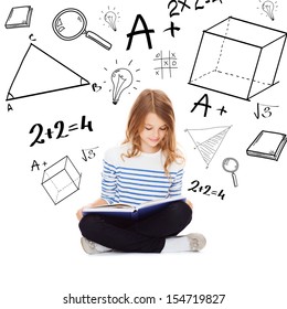 education and school concept - little student girl studying and reading book