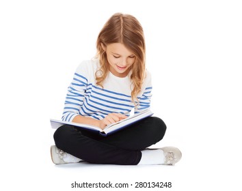 education and school concept - little student girl sitting on floor and reading book