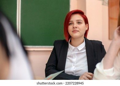 Education and school concept. A young girl at the desk watches and listens to the teacher. Generation Z - Shutterstock ID 2207228945