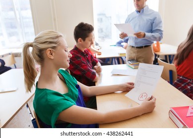 Education, School, Learning And People Concept - Group Of Students And Teacher With Test Results In Classroom