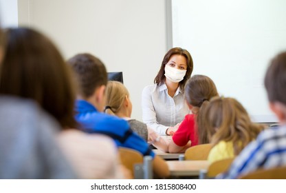 Education, School And Pandemic Concept - Teacher Wearing Face Protective Medical Mask For Protection From Virus Disease Teaching Group Of Students In Classroom