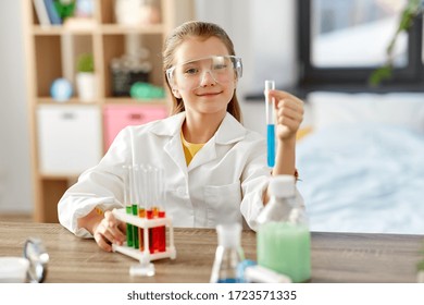 education, science and children concept - girl in goggles with test tube studying chemistry at home laboratory