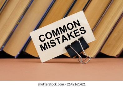 Education and science concept. On the table against the background of books is a business card with the inscription - Common Mistakes - Shutterstock ID 2142161421