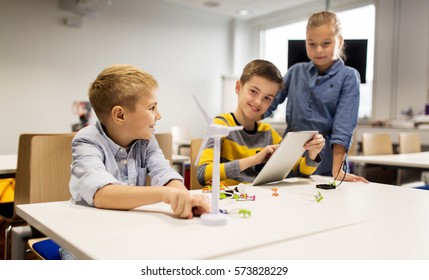 Education, Science, Technology, Children And People Concept - Group Of Smiling Kids Or Students With Tablet Pc Computer Programming Electric Windmill Toy At Robotics School Lesson