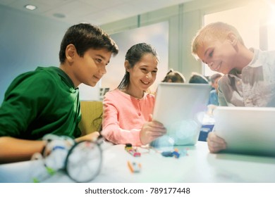 Education, Science, Technology, Children And People Concept - Group Of Happy Kids Or Students With Tablet Pc Computer Programming Electric Toys And Building Robots At Robotics School Lesson