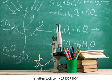 Education and sciences concept - books, molecule model and microscope on the desk in the auditorium, chalkboard background. - Powered by Shutterstock