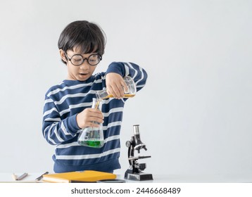 Education and smart children development concept. Little child boy performing science experiments on the table. Intelligence schoolboy enjoy and fun learning and testing chemistry lab experiment.