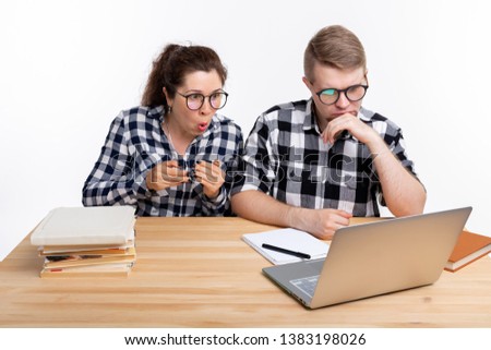 Education, students, people concept - a couple of teens in glasses are scared of something during looking in laptop