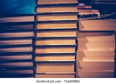 Education and Study as concept, Book stack and blurred bookshelf in the public library room. Vintage retro tone and Selective focus.