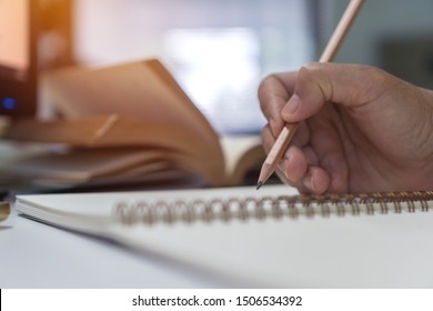 Education study concept : Student writing documents or signing notebook for learning studying and read book on desk in library for learn by self at university or college with oldbook background