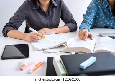 Education, teaching, learning, technology and people concept. Two high school students or classmates with helps friend catching up workbook learning in classroom, Tutor books with friends.